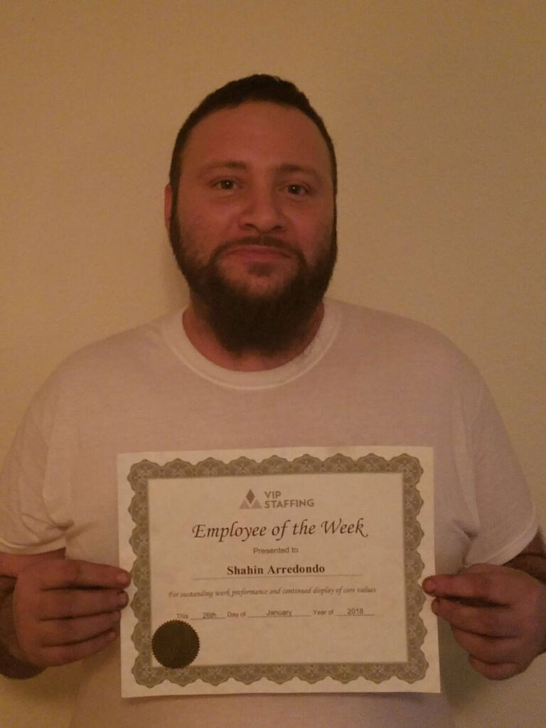 Man holding "Employee of the Week" certificate from VIP Staffing, showcasing gratitude and success in employment.