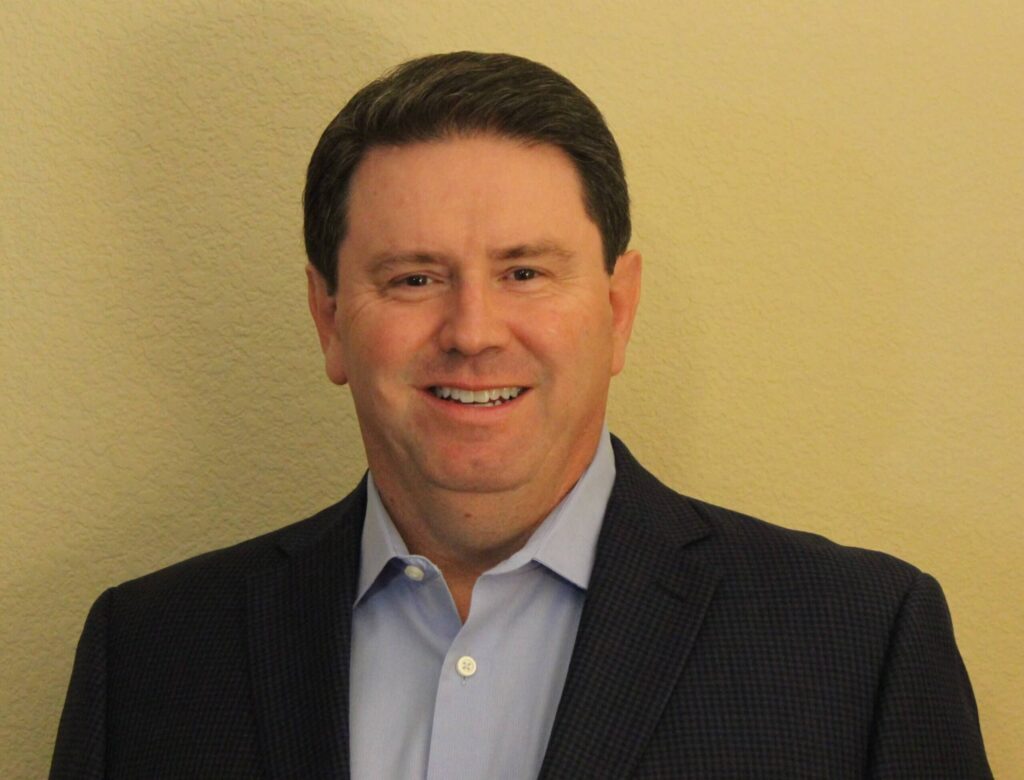 Smiling man in a professional suit against a neutral background, representing VIP Staffing's supportive and professional approach to job placement.
