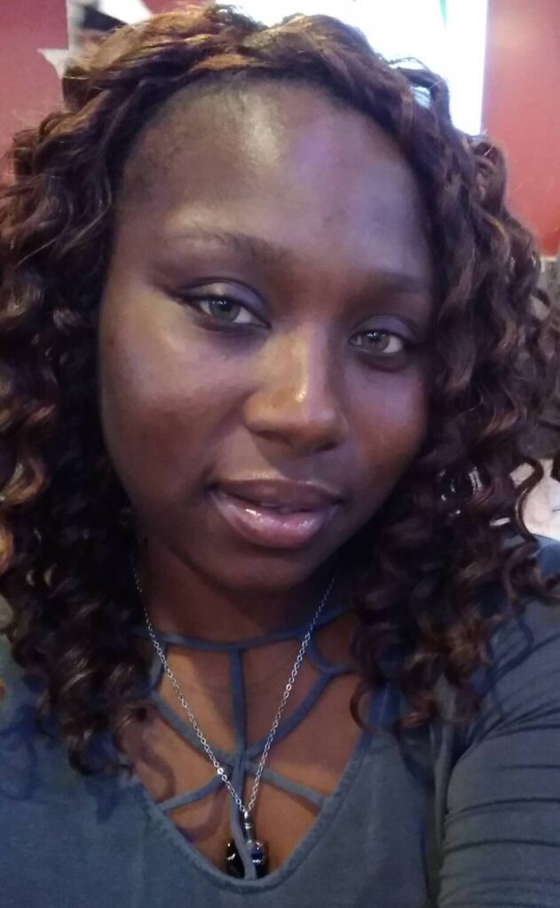 Woman with curly hair smiling, wearing a gray top, representing success stories from VIP Staffing.