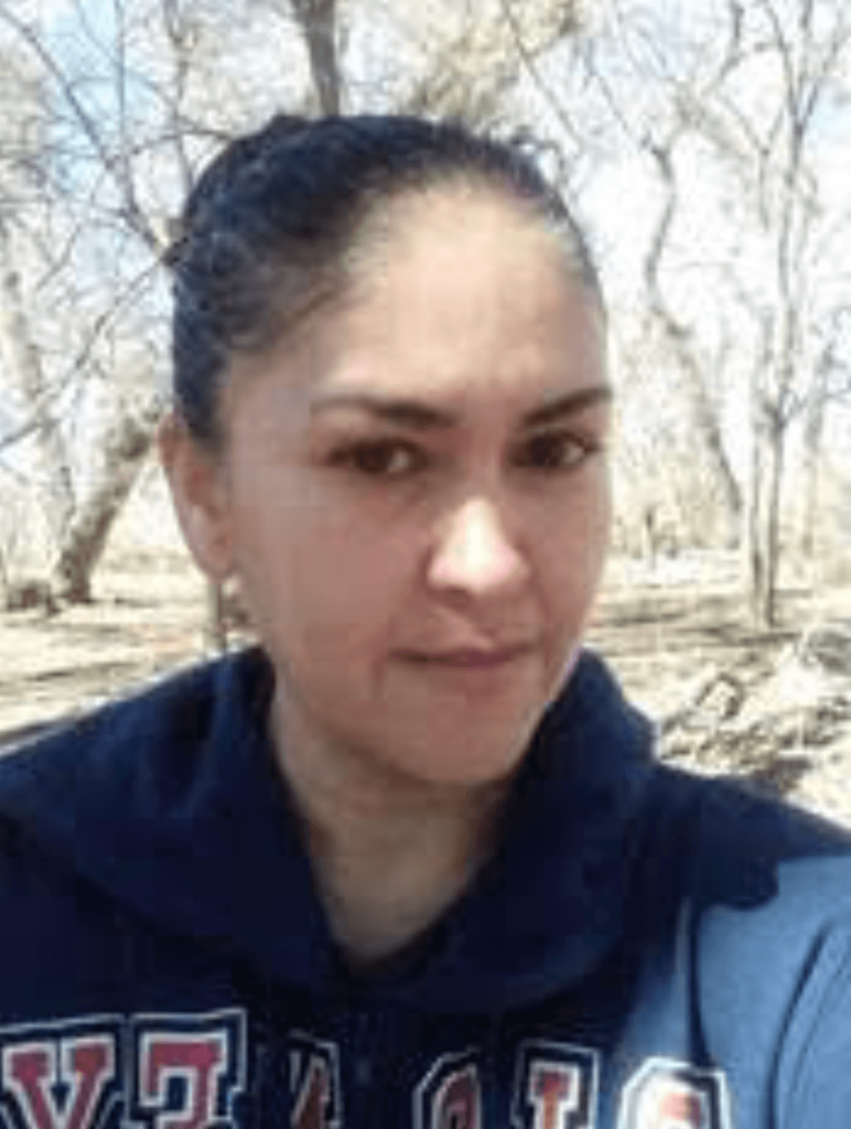 Woman wearing a navy hoodie, smiling softly, in a natural outdoor setting with bare trees, representing personal success and stability through VIP Staffing.