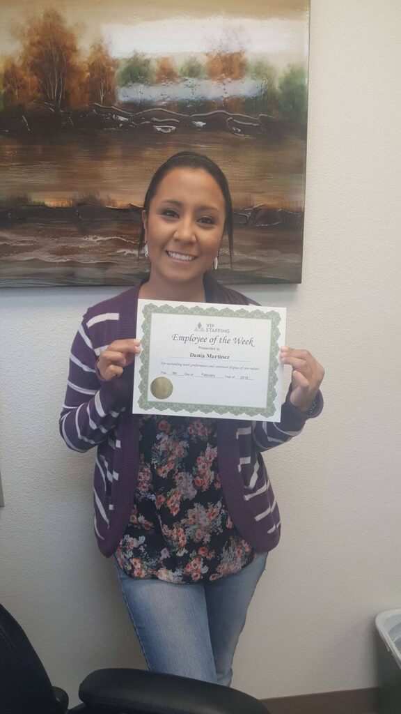 Employee of the Week holding certificate from VIP Staffing, smiling in office setting, showcasing success story in the workplace.