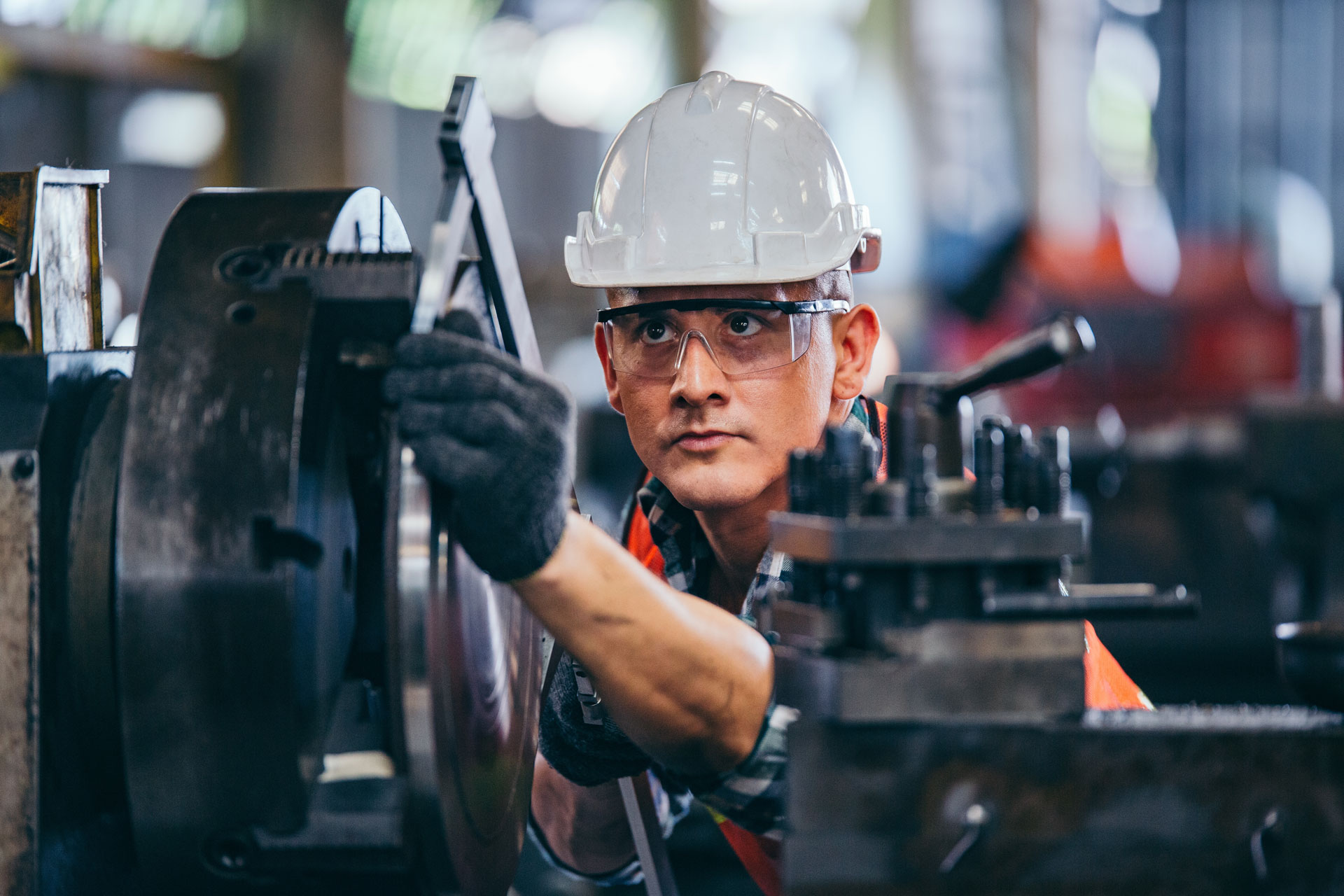 Manufacturing worker in hard hat and safety glasses operating machinery, showcasing skilled trades and reliable staffing solutions for industrial needs.